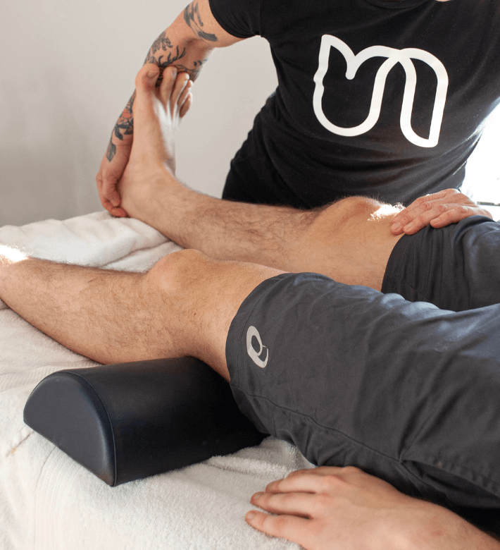 Massage therapist performs leg stretch in sports massage