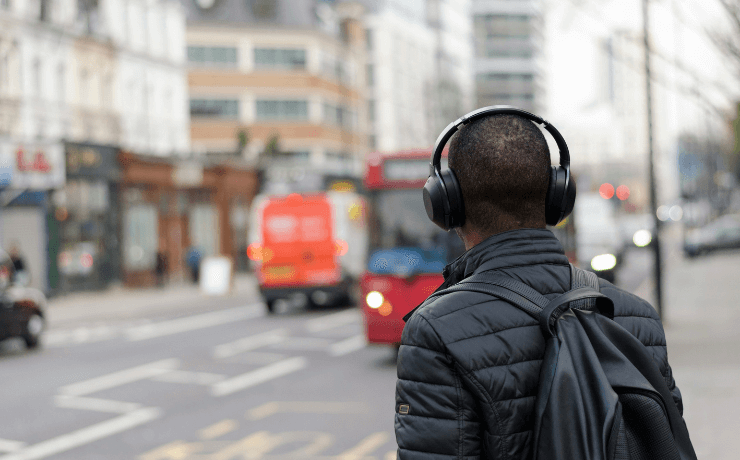 Man listening to audiobook walking with London bus in background
